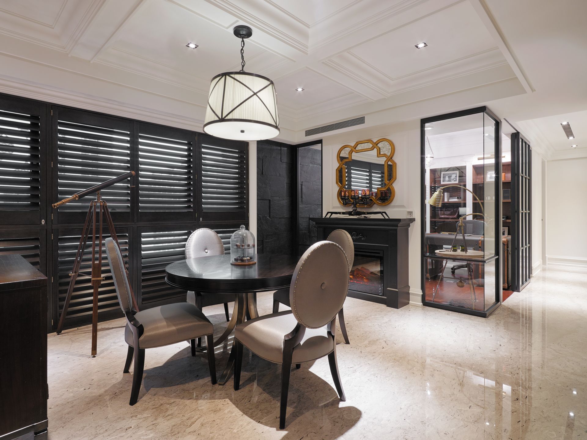 Dining room with dark round table and chairs, pendant light, black shutters, and glass display case.