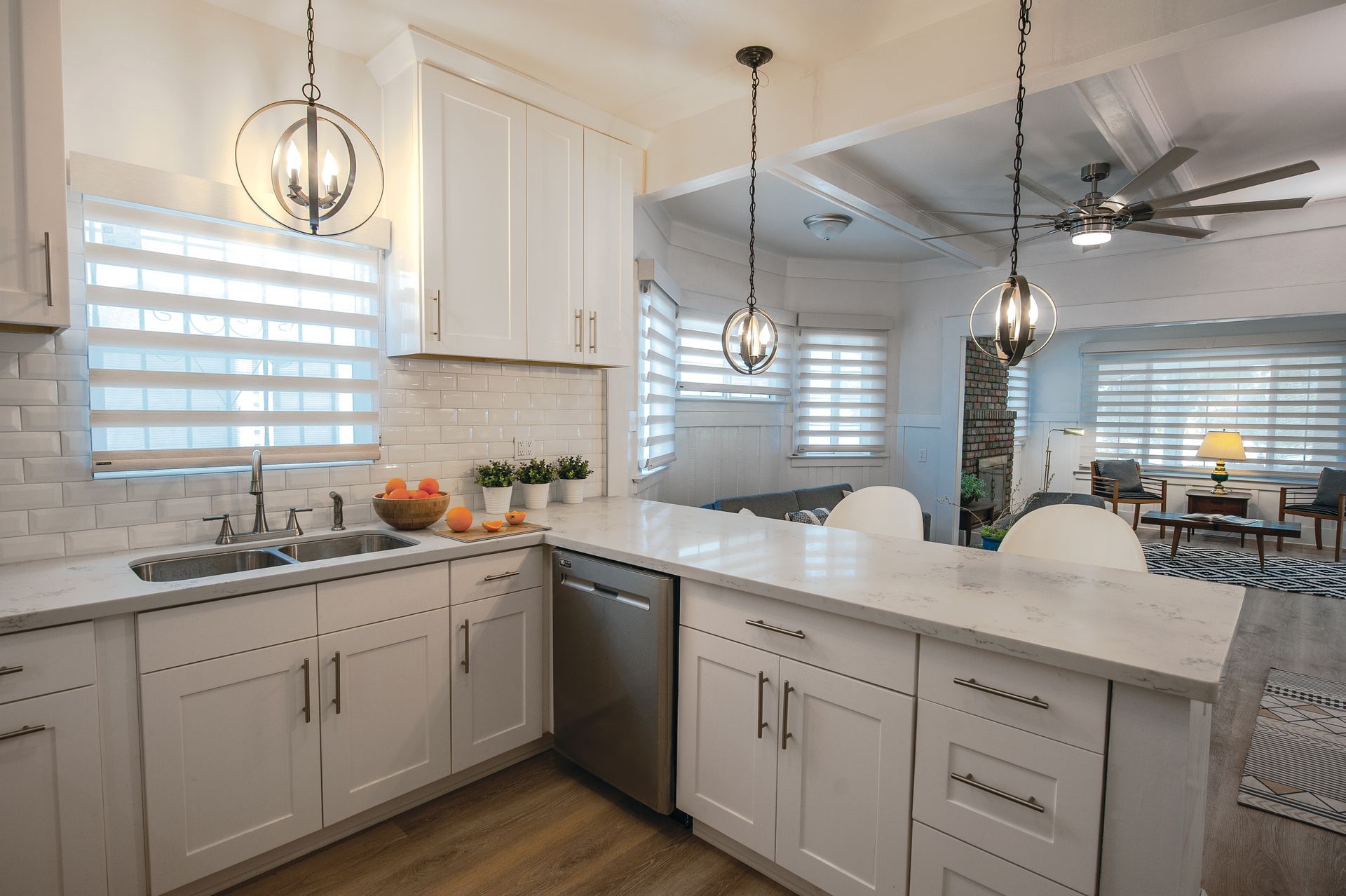 White kitchen with marble countertops, stainless steel appliances, and pendant lights.