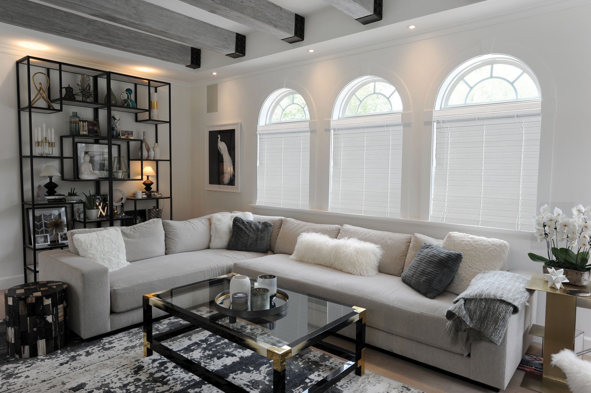 Living room with sectional sofa, black metal shelving unit, and arched windows.