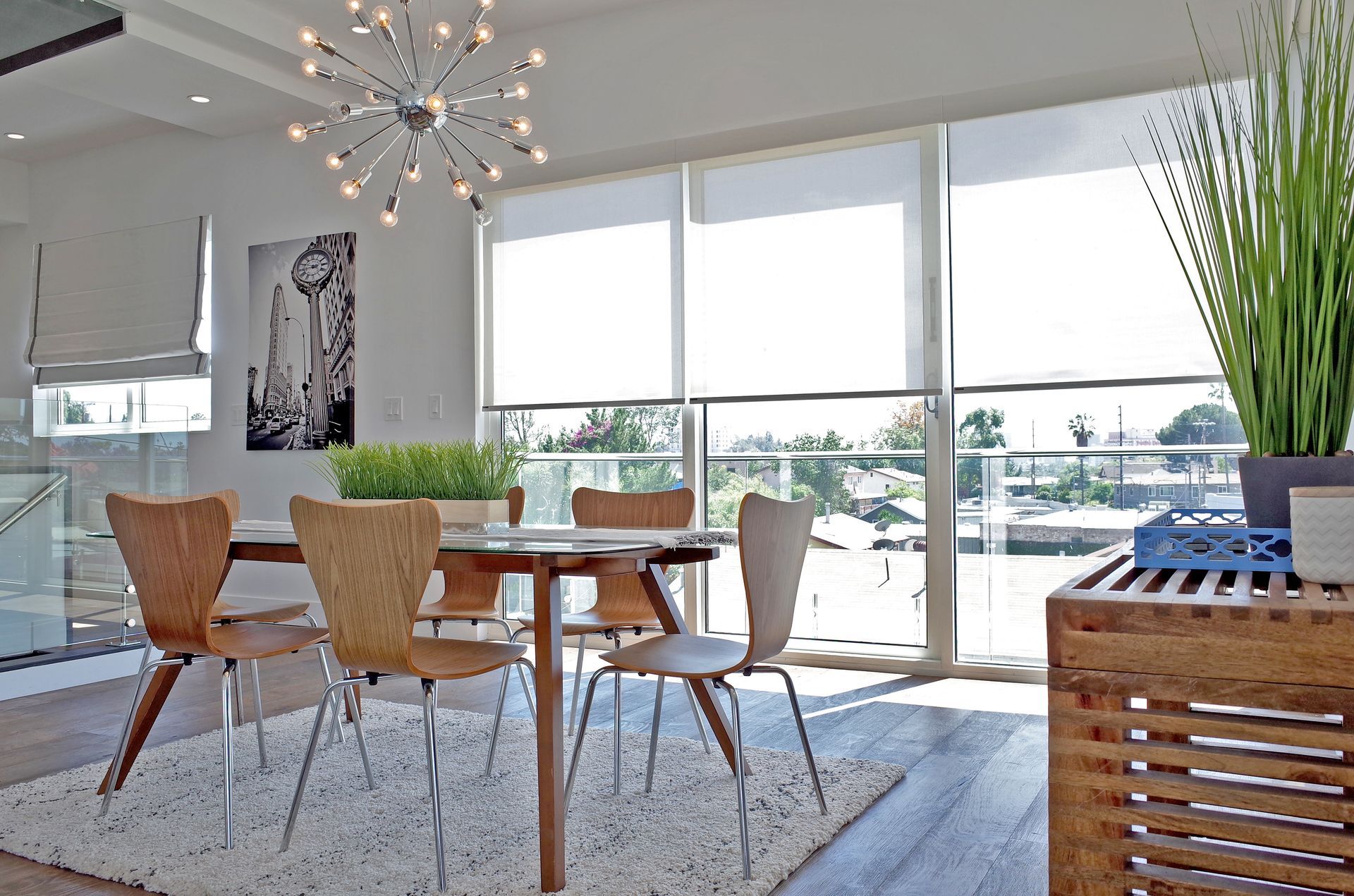 Dining room with a wooden table and chairs, large windows, and a fluffy white rug.