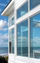 Modern white beachfront house with large windows overlooking the ocean and blue sky