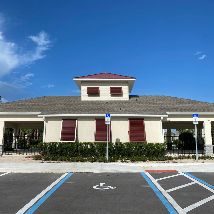 Accessible parking spaces in front of a low building with red shutters under a blue sky