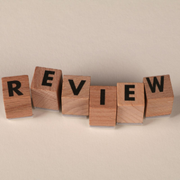 Wooden letter blocks spelling “REVIEW” on a beige background