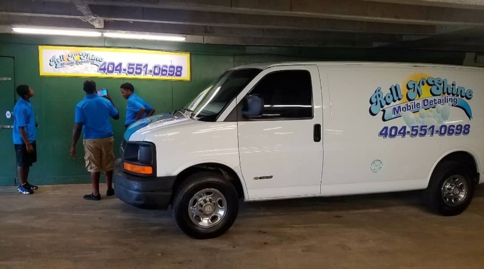 A white van is parked in a parking garage with three men standing next to it.