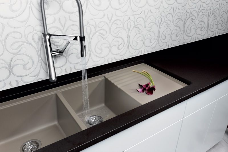 A kitchen sink with a faucet and flowers on the counter