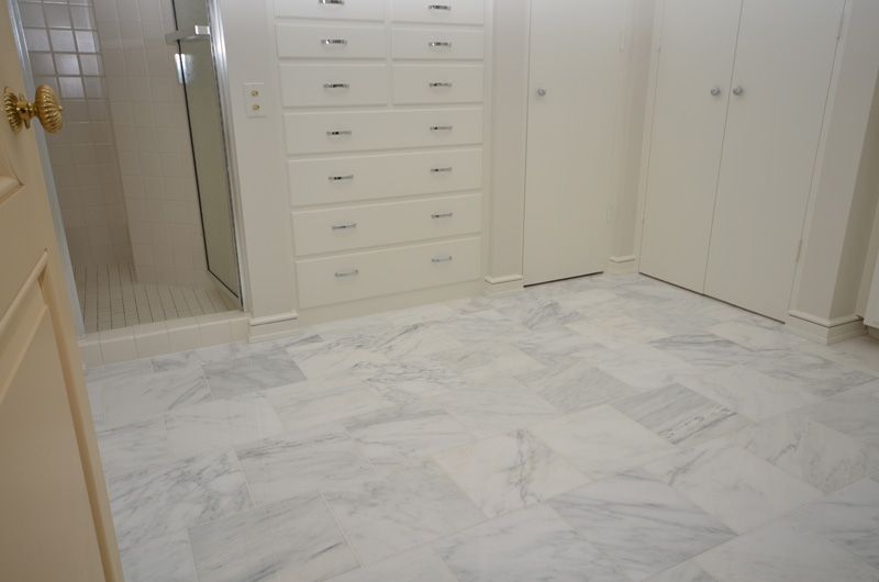 A bathroom with a marble floor and white cabinets