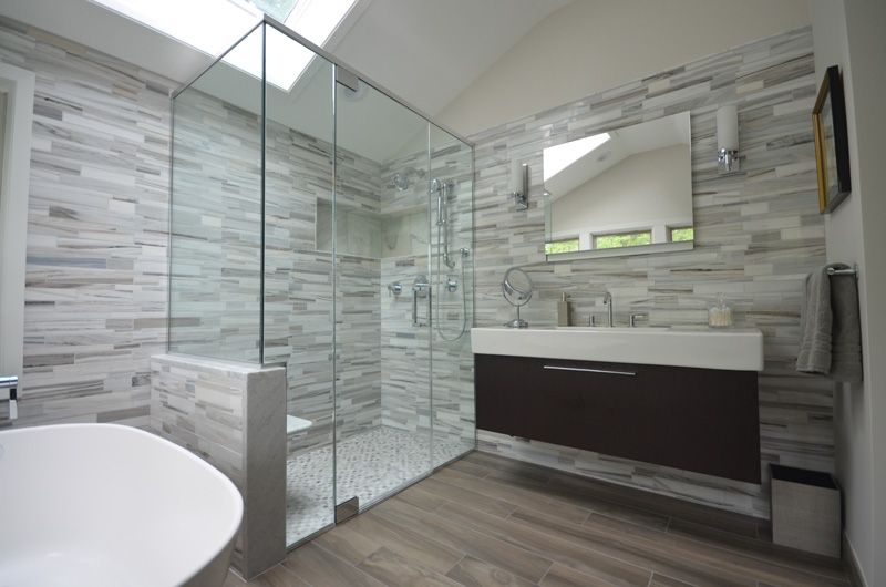 A bathroom with a walk in shower , sink and mirror.