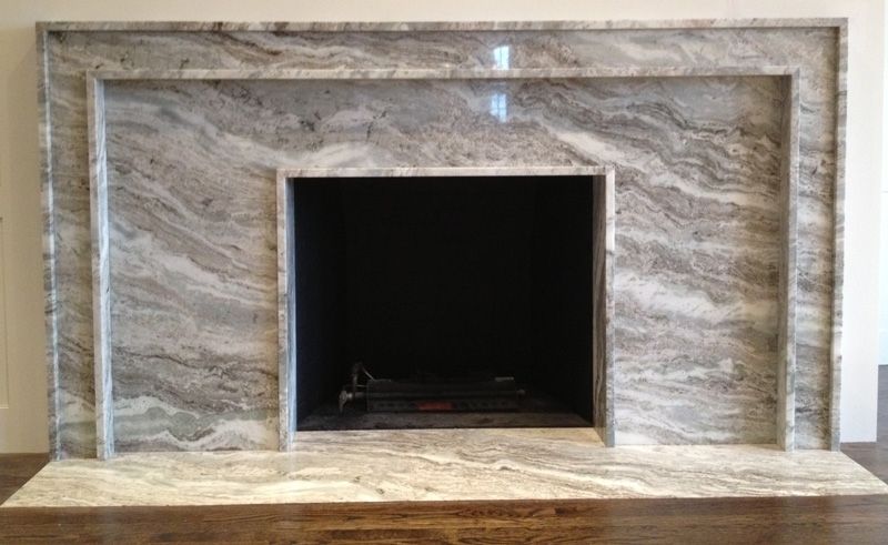 A fireplace with a marble mantle and surround in a living room.