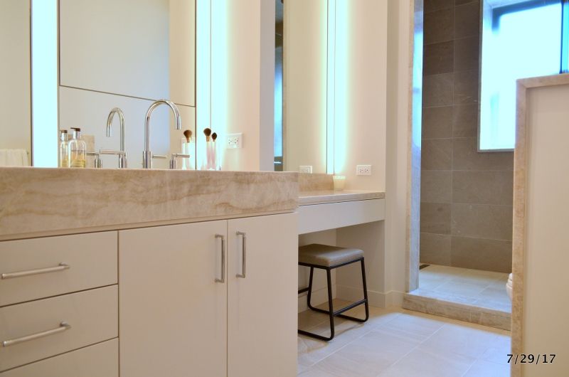 A bathroom with two sinks , two mirrors and a stool.