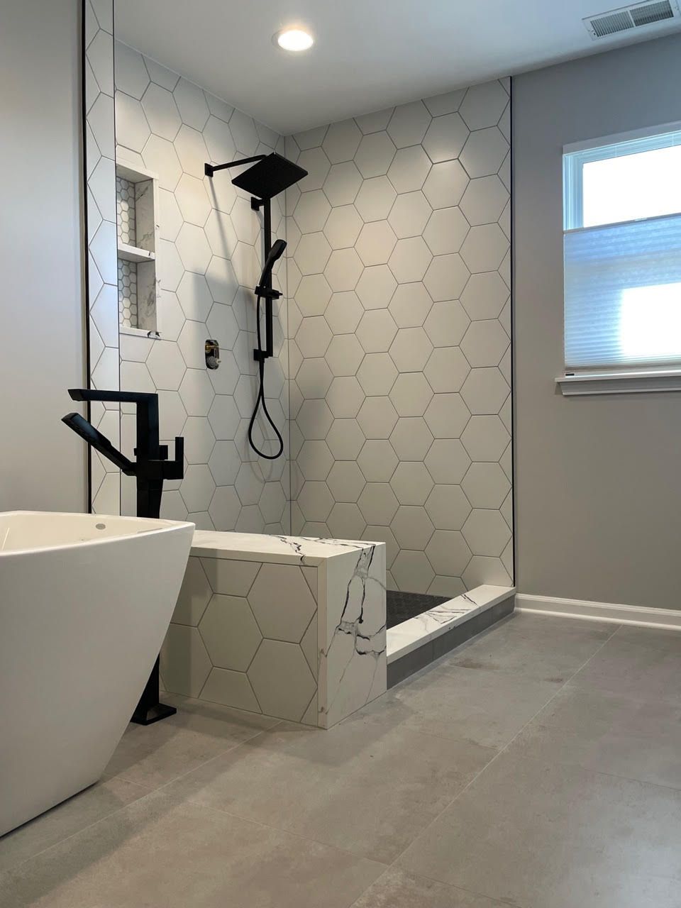 A bathroom with a tub , shower , and window.