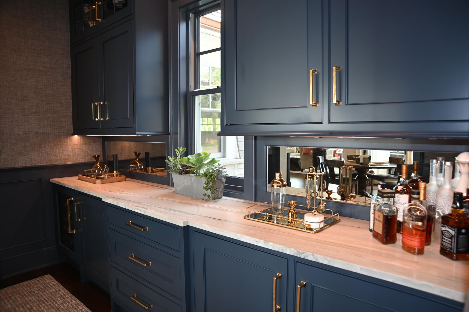 A kitchen with blue cabinets and a bar with bottles on the counter.