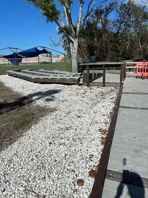 Accessible boardwalk ramp beside a gravel path, with shaded benches and blue canopy under a clear sky.