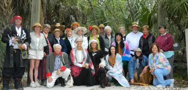 Group in colorful costumes posing outdoors in front of lush palm trees