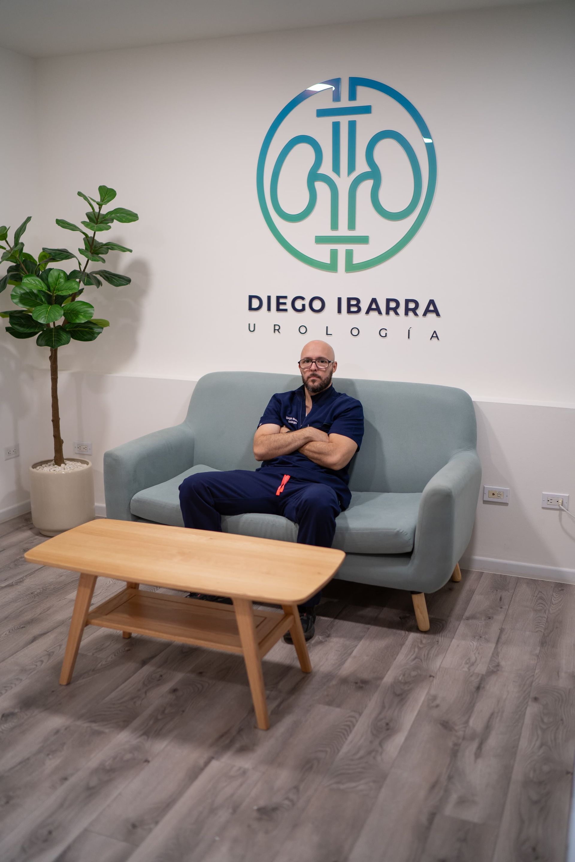 Un hombre está sentado en un sofá frente a un cartel que dice Diego Ibarra.