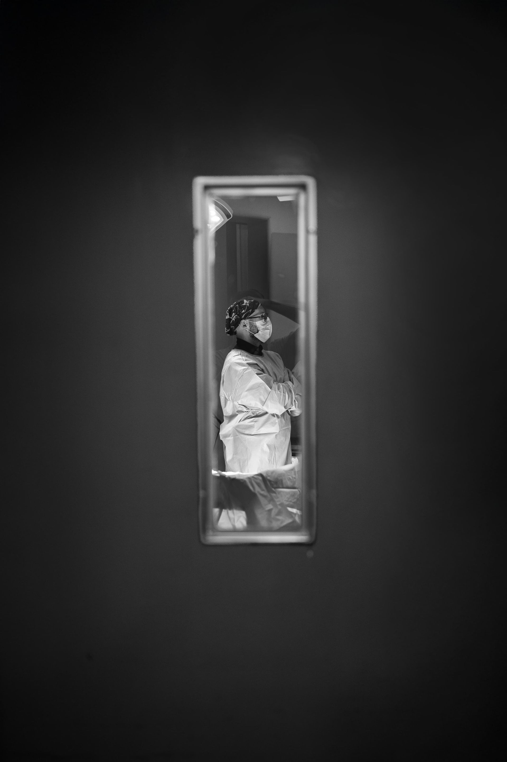 Una fotografía en blanco y negro de una persona parada frente a un espejo.