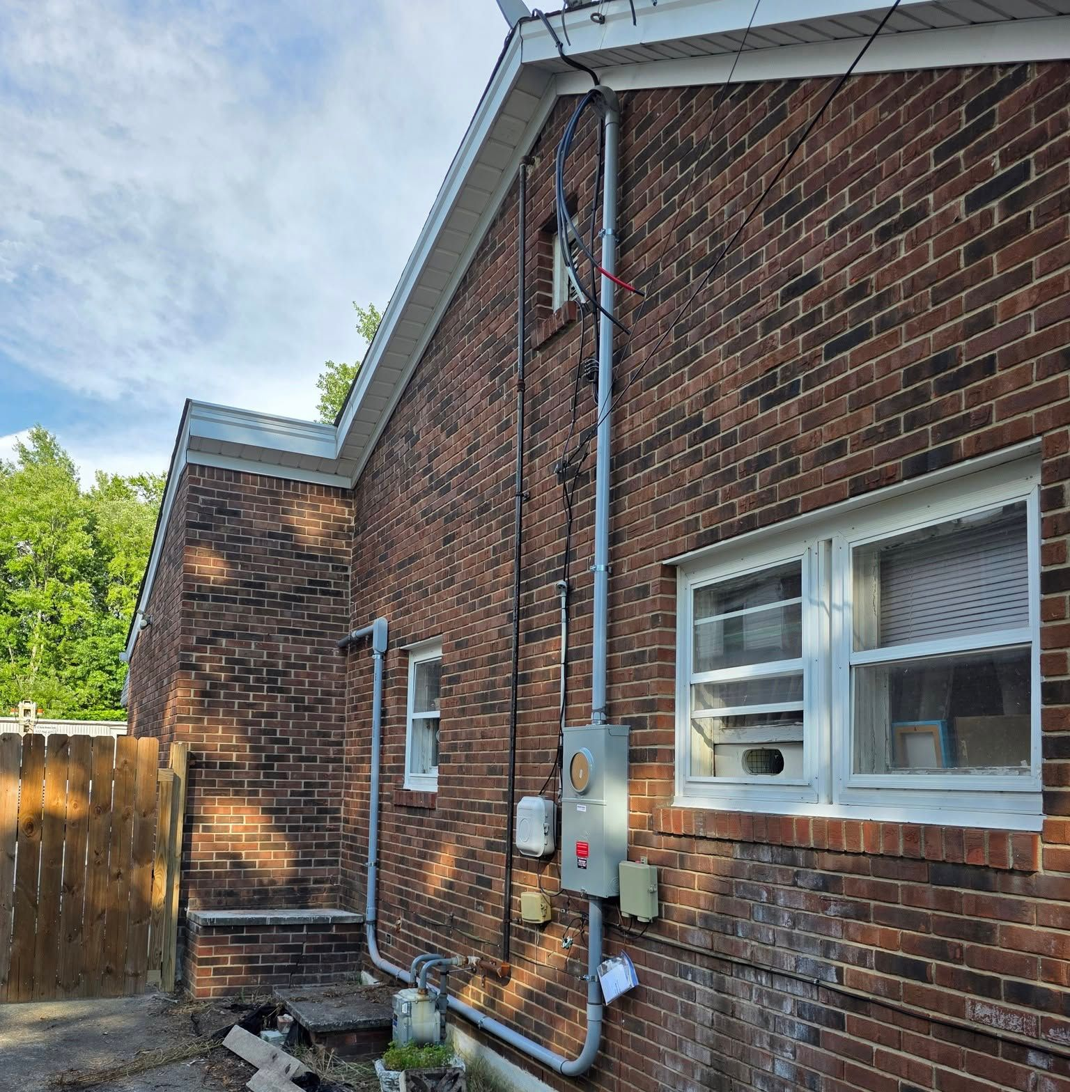 Brick building exterior with conduit, meter box, and windows.