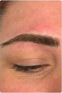 Close-up of a closed eye with a shaped eyebrow and a red, irritated area above the brow