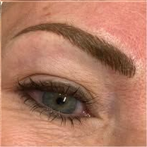 Close-up of an eye with long false eyelashes and a dark, sharply shaped eyebrow.