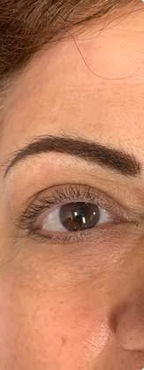 Close-up of a woman’s eye and eyebrow with natural makeup on a light background