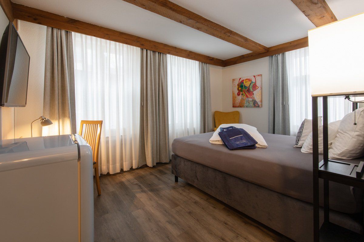 Ein Hotelzimmer mit Bett, Schreibtisch, Stuhl und Fernseher.
