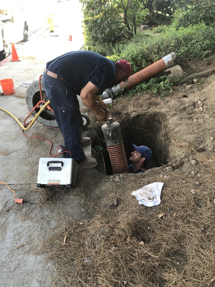 A man is working on a pipe in a hole in the ground.