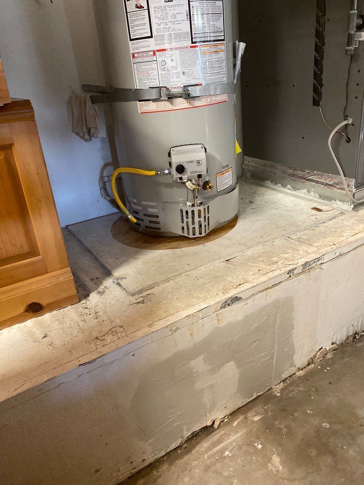 A gas water heater is sitting on the floor in a room.