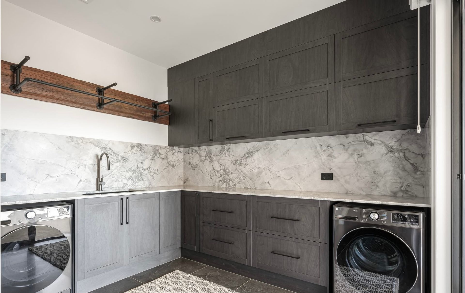 A Laundry With Black Counter Tops And dark Cabinets — Content Stone In Trenayr, NSW