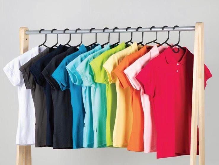 Una fila de polos coloridos cuelgan de un estante.