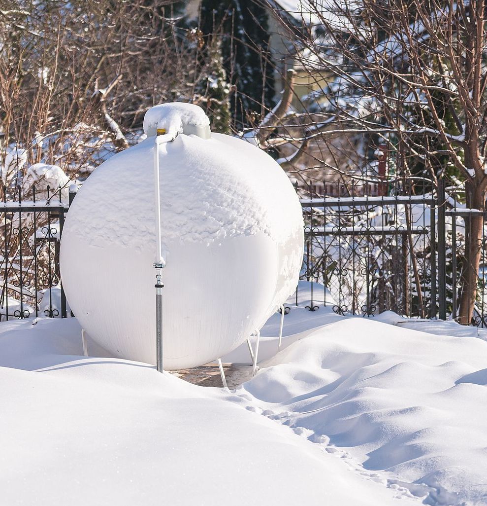 A propane tank covered in snow is sitting in the snow.