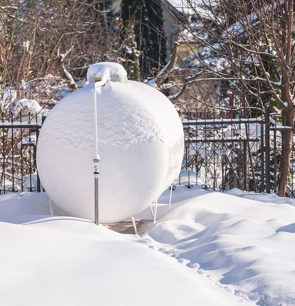 A propane tank covered in snow is sitting in the snow.