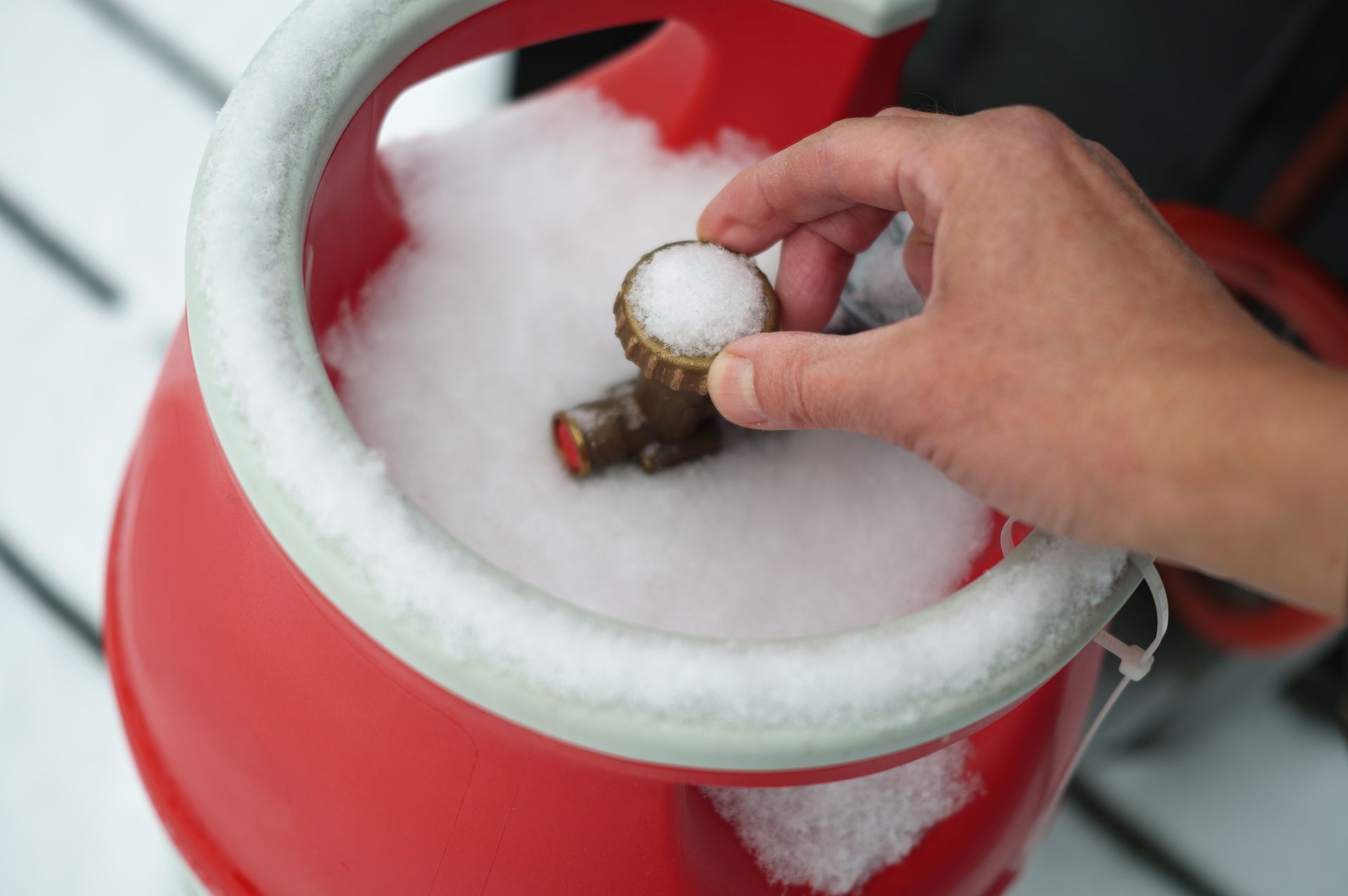 A propane tank covered in snow is sitting in the snow.