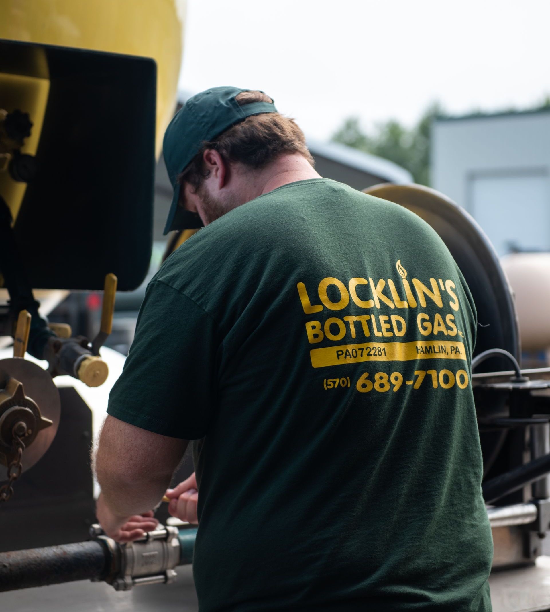 A man wearing a green shirt that says locklin 's bottled gas