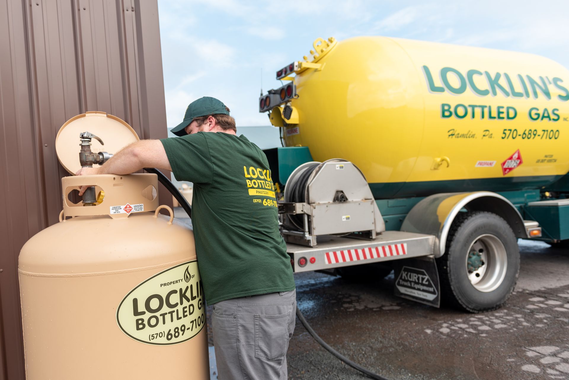 A man is loading a bottle of gas into a truck.