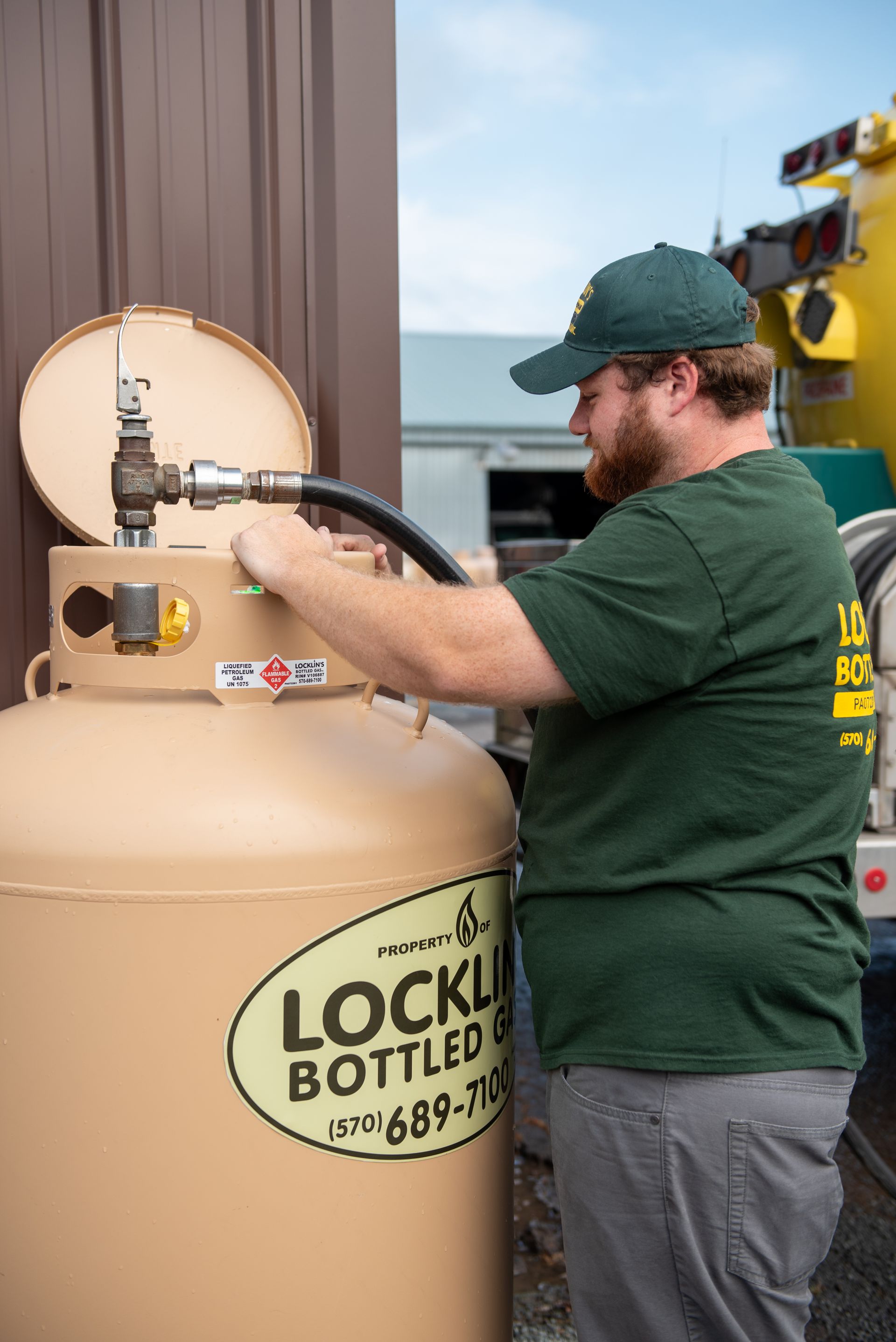 A man is filling a propane tank with a hose.