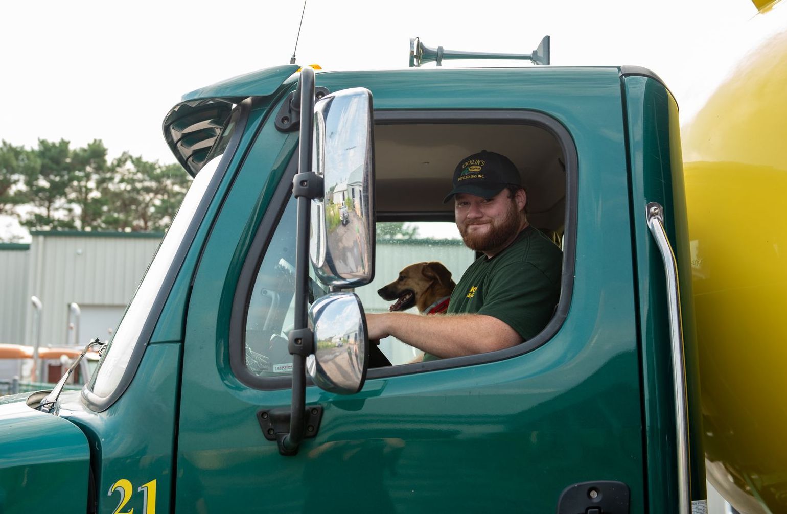 A man is driving a truck with a dog in the driver 's seat.