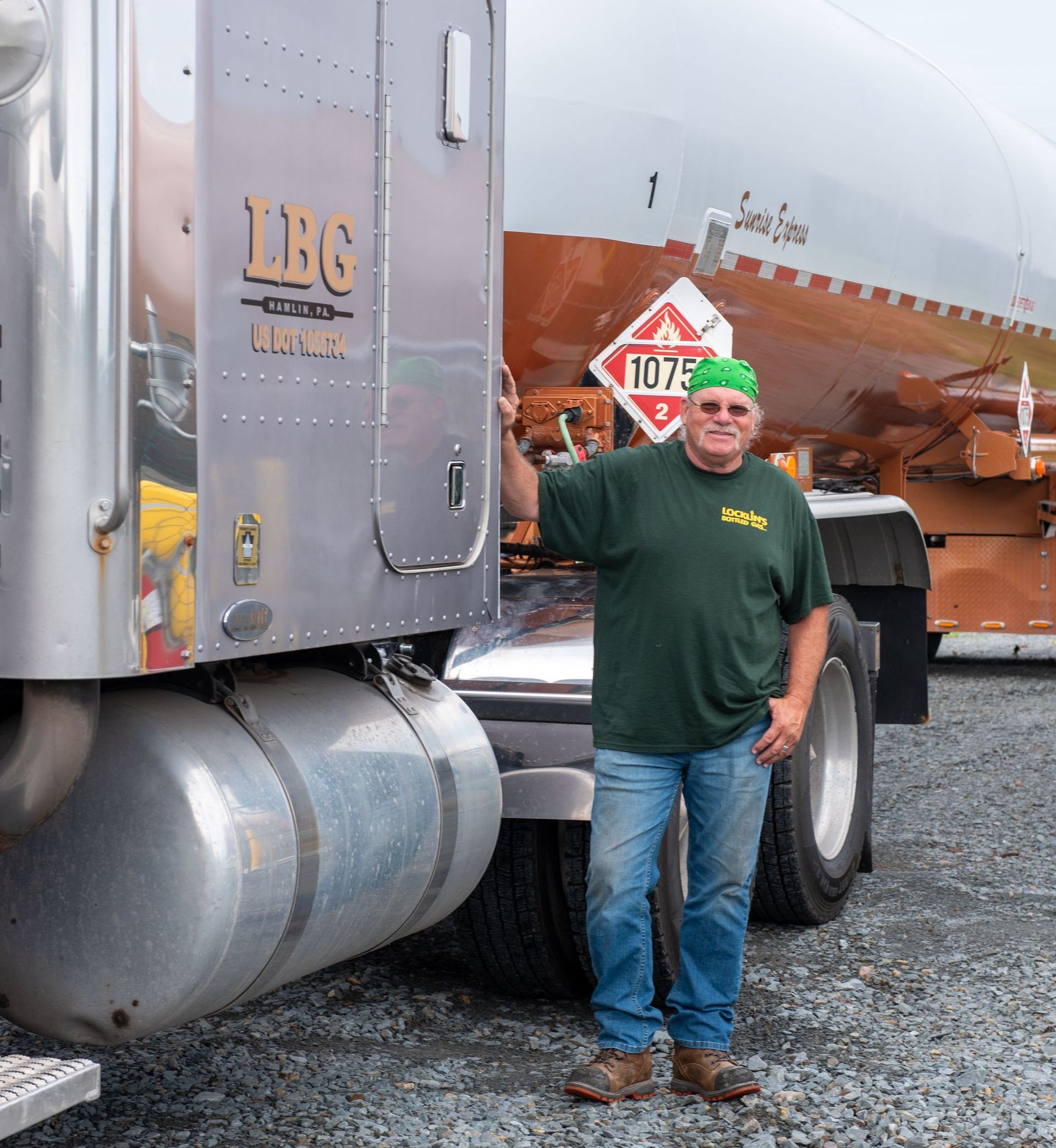 A man in a green shirt is standing in front of a truck that says lbg