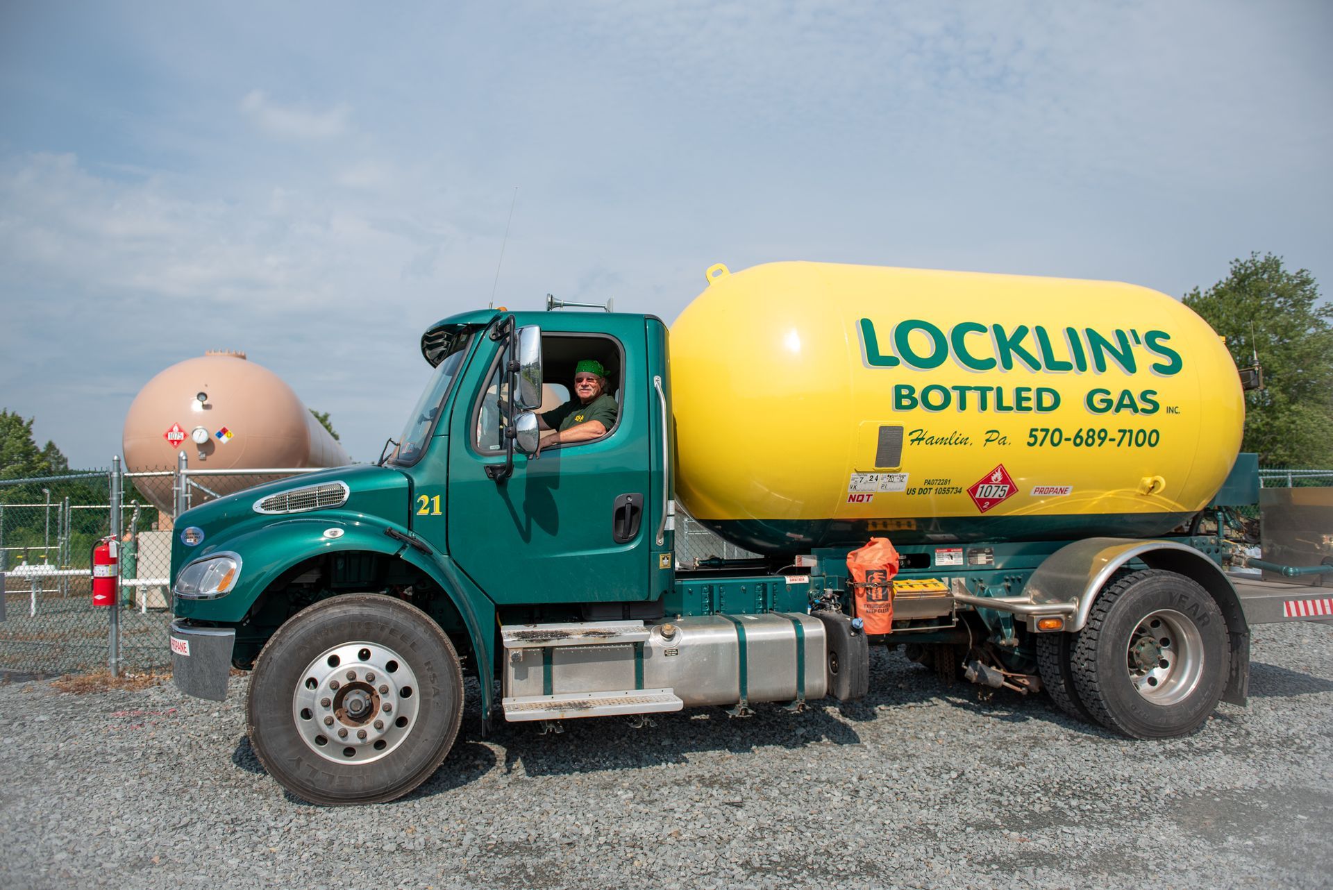 A bottled gas truck is parked in a gravel lot.