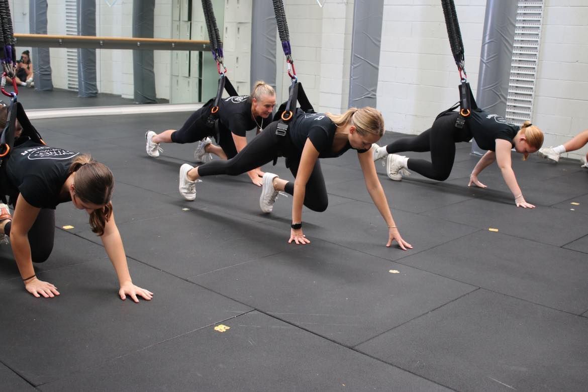 A group of women are doing push ups in a gym.