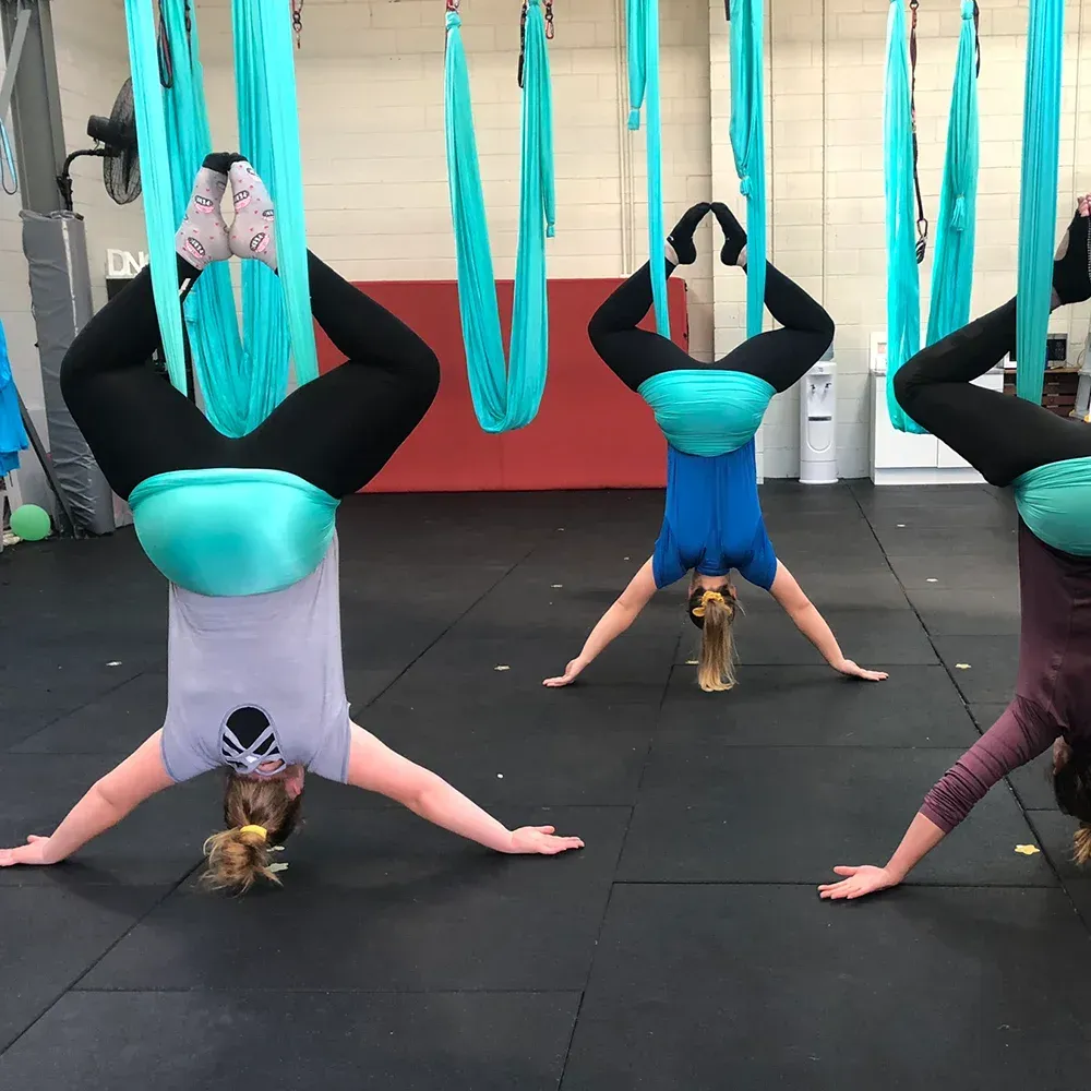 A group of women are doing aerial yoga in a gym