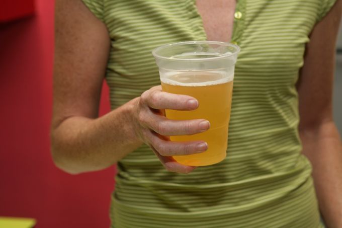Una mujer sostiene una taza de cerveza en su mano.