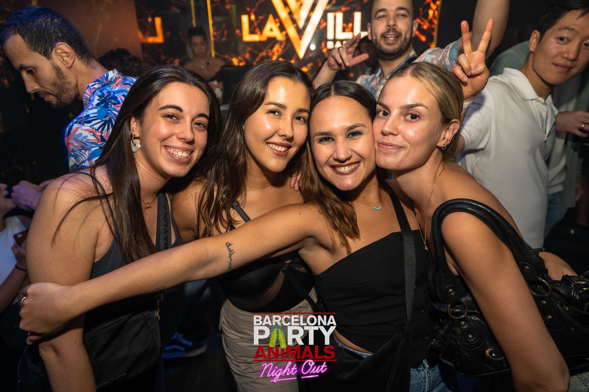 Gente en una discoteca posando para una foto, sonriendo.