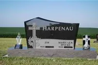 A black gravestone with a cross on it is in a cemetery.