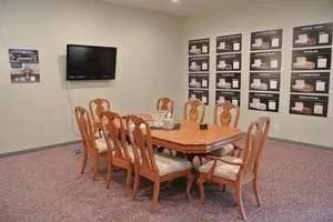 A conference room with a table and chairs and a flat screen tv.