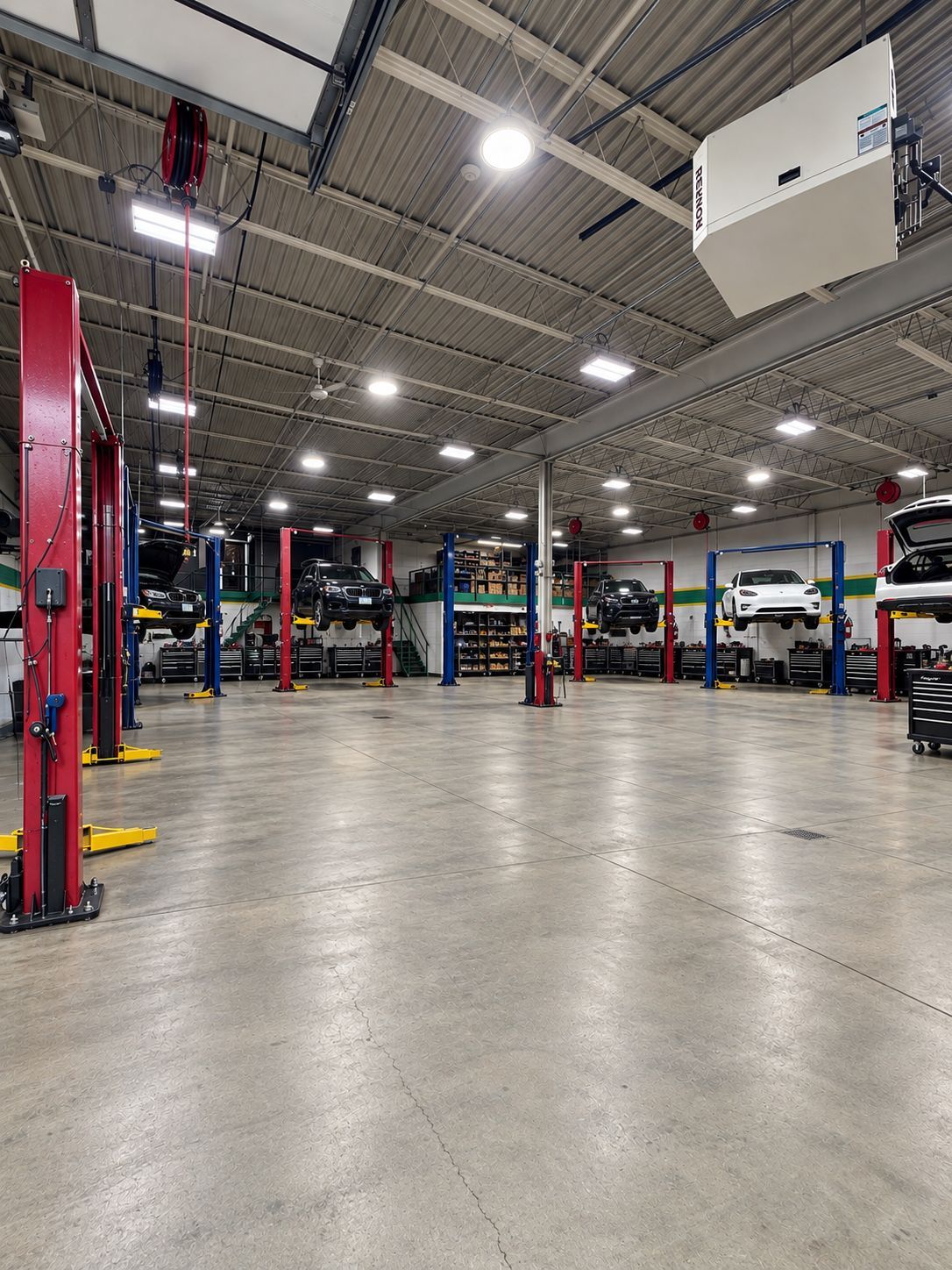 Empty auto repair garage with red car lifts, concrete floor, and bright overhead lights | Yaffo Auto Service