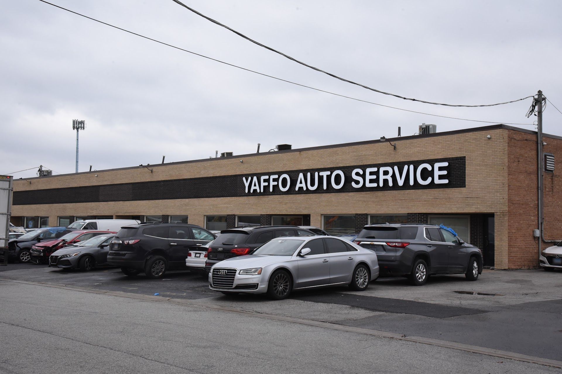Yaffo Auto Service storefront with parked cars along a brick building | Yaffo Auto Service