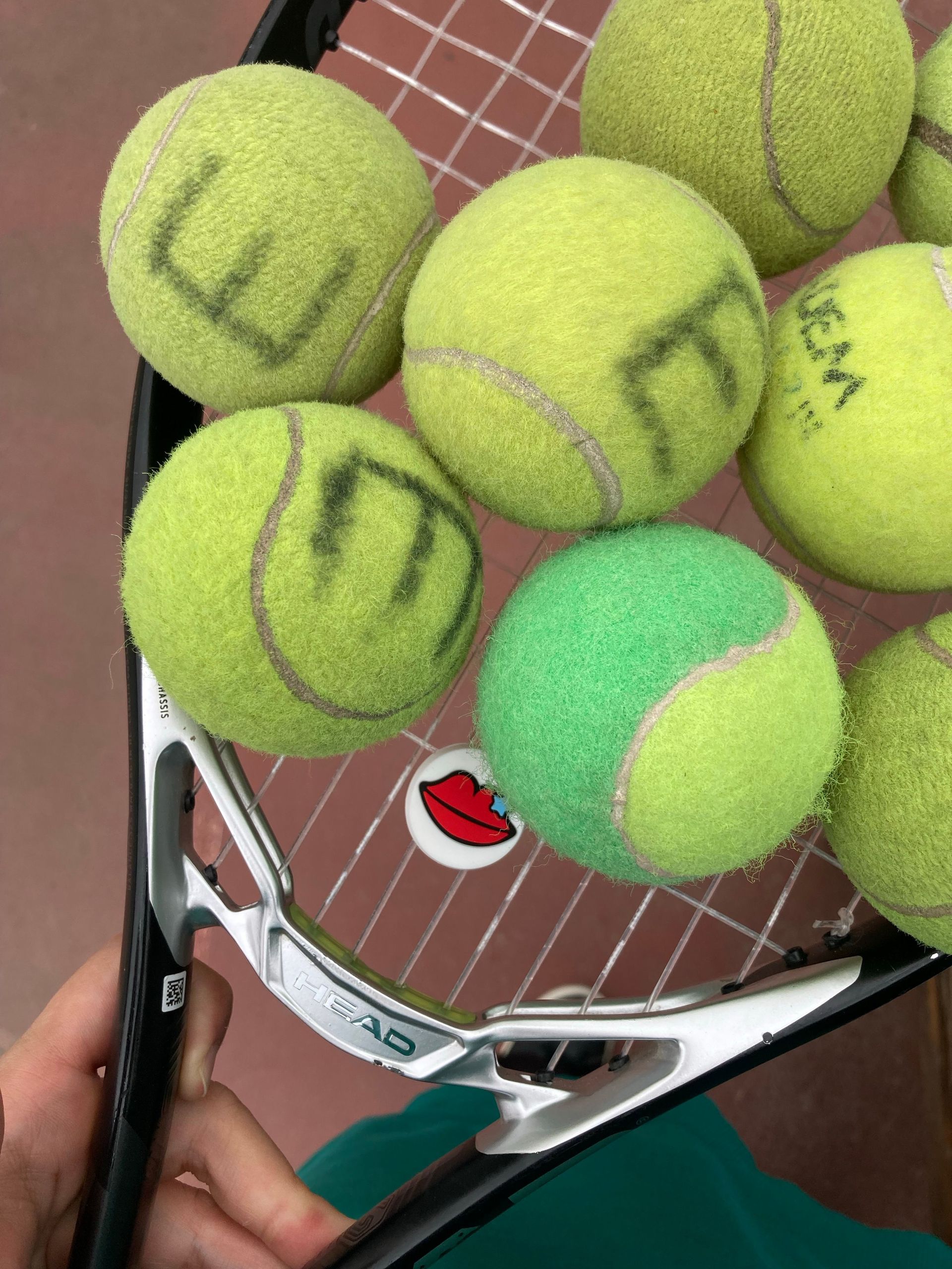 Tennis racket catching several tennis balls, close-up on the strings.
