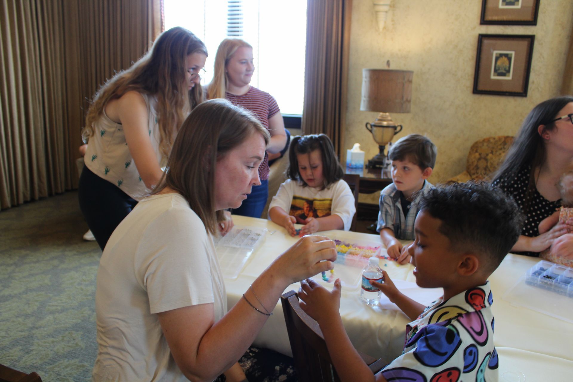 Children and adults sitting around a table, creating crafts in a bright room