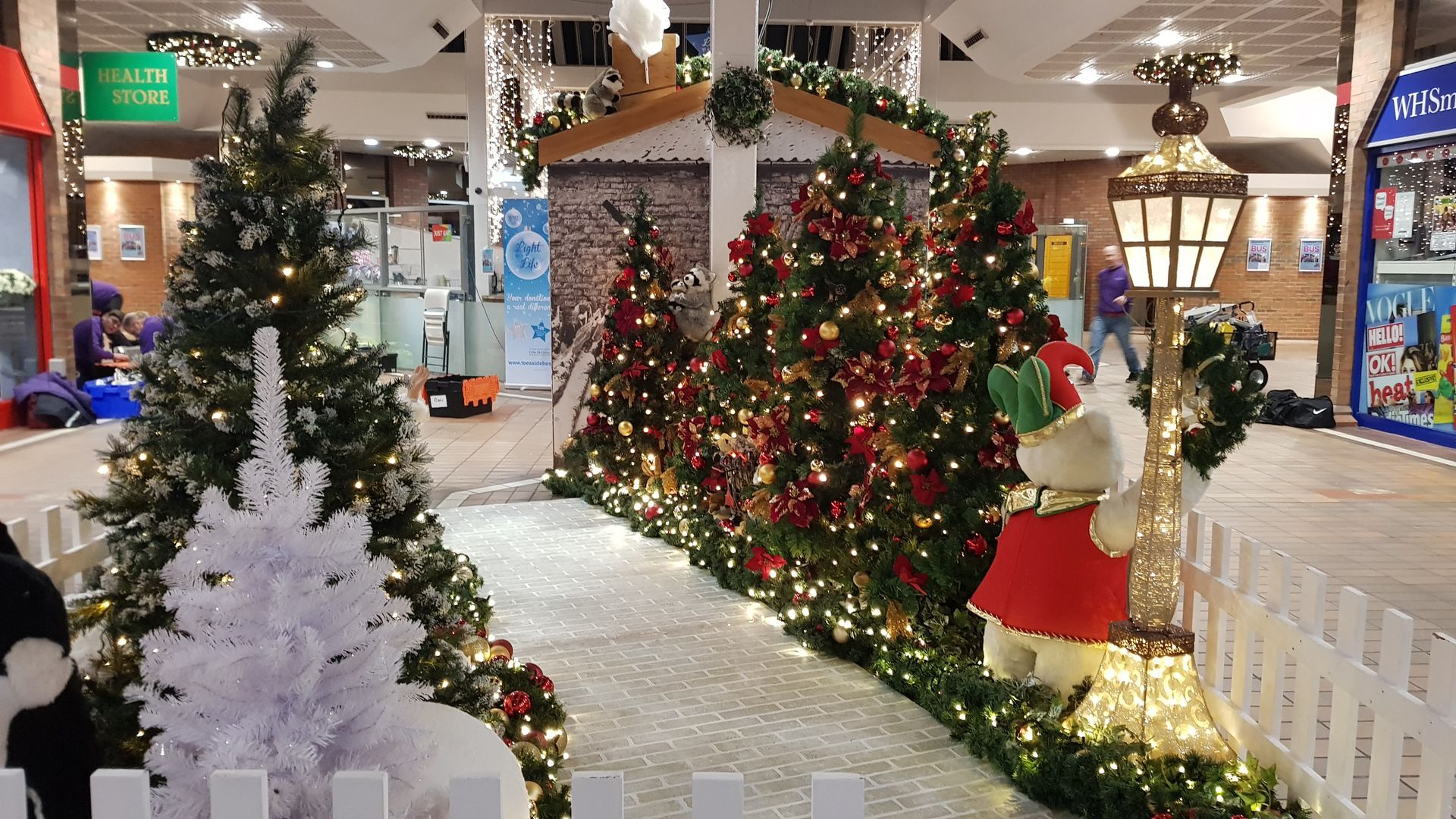 A row of christmas trees and decorations in a mall.