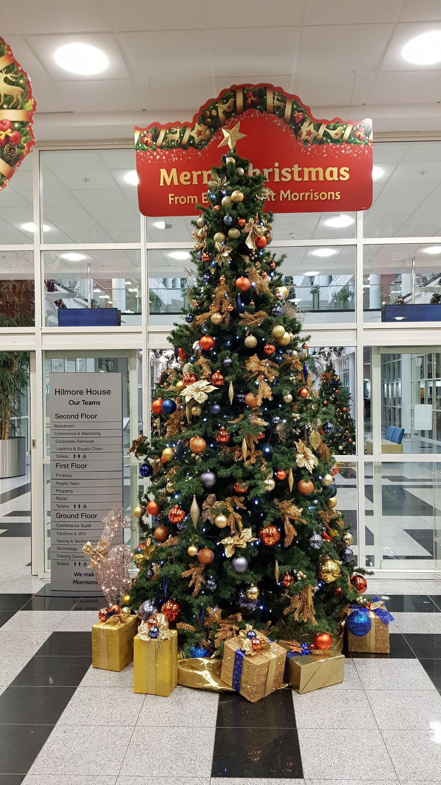A christmas tree with gifts underneath it and a sign that says merry christmas.