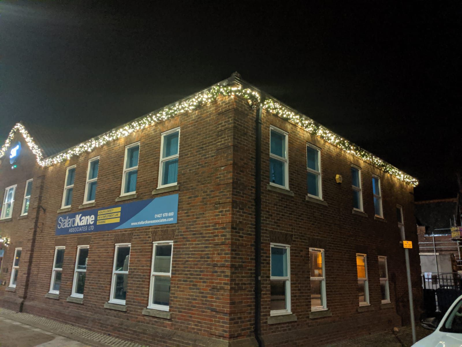 A large brick building with christmas lights on it at night.